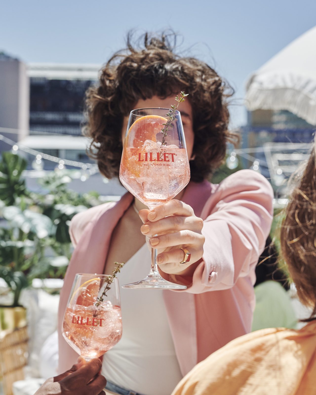 Girl holding a Lillet Pink Spritz glass with grapefruit and thyme